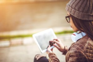 Business young woman sitting in park and working on tablet