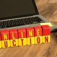 Träklossar med texten ONLINE AUCTION framför en laptop.
