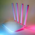 Vit wifi-router med fyra antenner belyst i rosa och blått